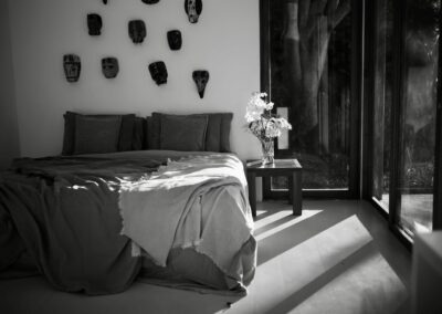 A spacious room at Anzan Atitlán featuring a king-size bed, hardwood floors, and a large outdoor covered lounge area with stunning open views of Lake Atitlán.